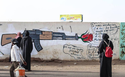 兩名婦女在喀土穆看一支槍和一朵玫瑰的塗鴉 (圖片來源: Twitter@Safiaib38469578）