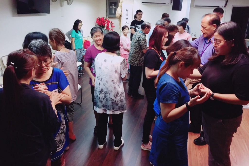 愛鄰教會中，台灣同工為馬來西亞弟兄姊妹按手禱告。（蔡明憲／攝影）