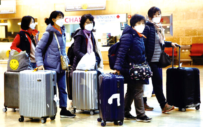 2020年2月24日，戴著口罩的韓國遊客在以色列本古里昂機場提著行李，被以色列規定立即返回韓國。(AP PHOTO/ Ariel Schalit)