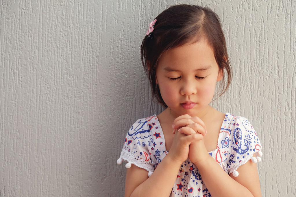 asian little girl praying with eyes closed