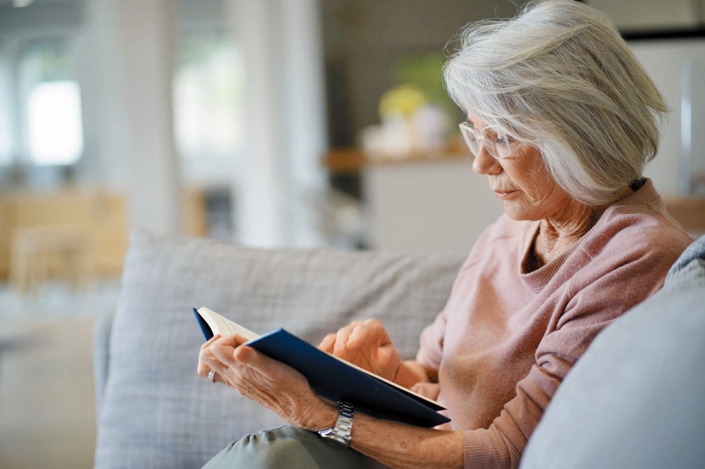 Senior woman reading on couch at home